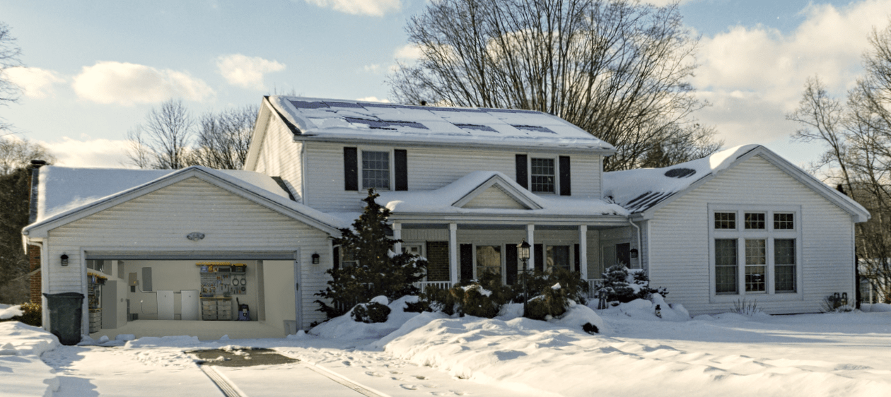 White house with black shutters keeps the lights on during a winter storm with solar and home backup
